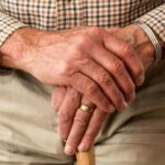 Elderly hands resting on a cane, symbolizing age and support.