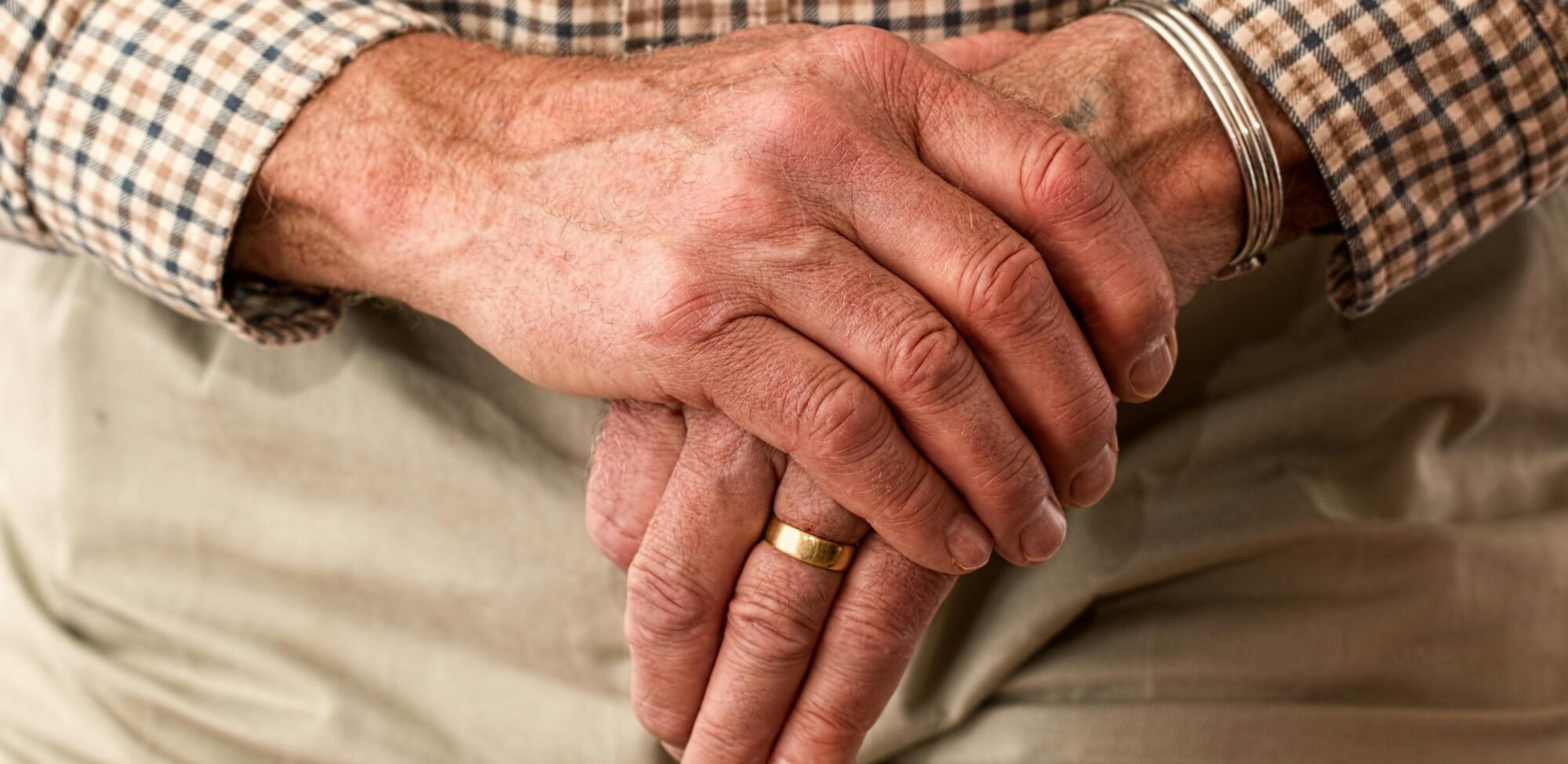 Elderly hands resting on a cane, symbolizing age and support.