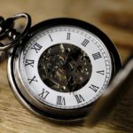Close-up of an antique pocket watch showing Roman numerals.