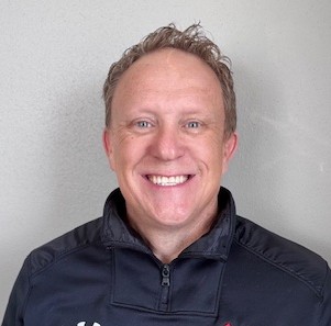 Smiling man in a dark jacket.