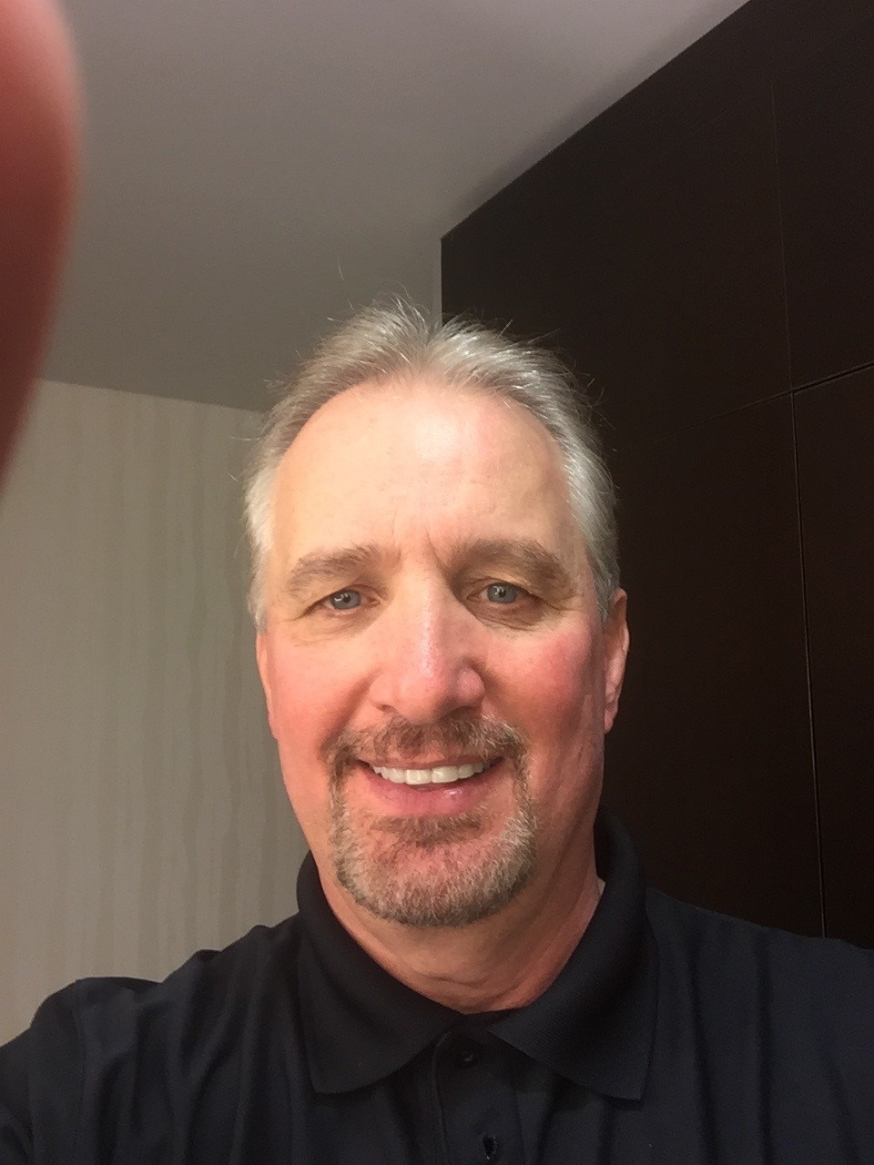 Smiling middle-aged man with gray hair and goatee indoors.